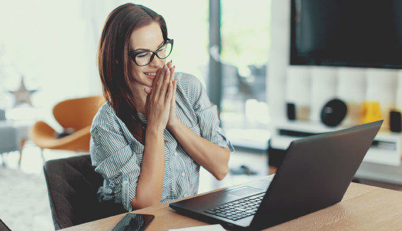 Frau sitzt vor Laptop und freut sich